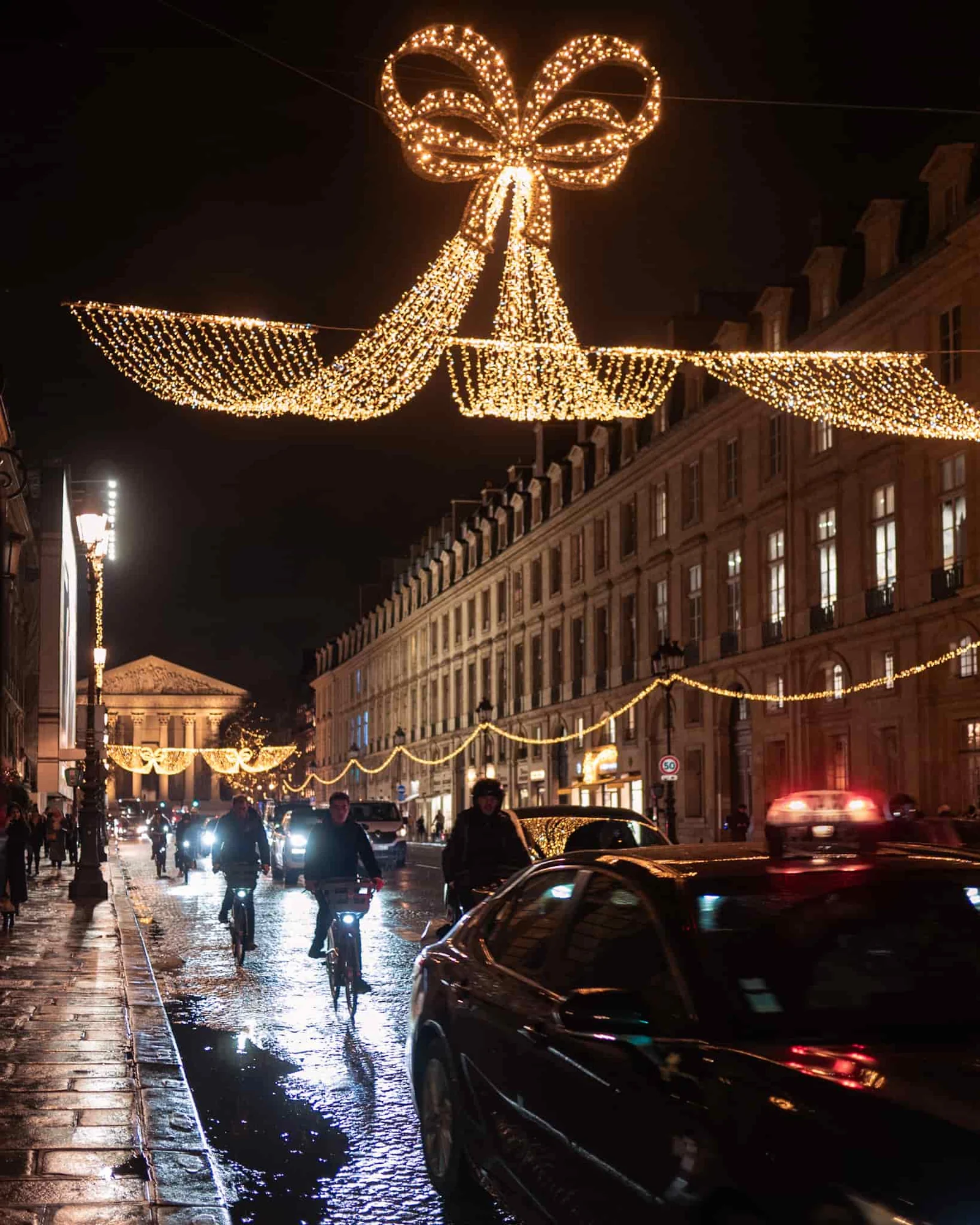 A Paris street with traffic decorated with Christmas lights