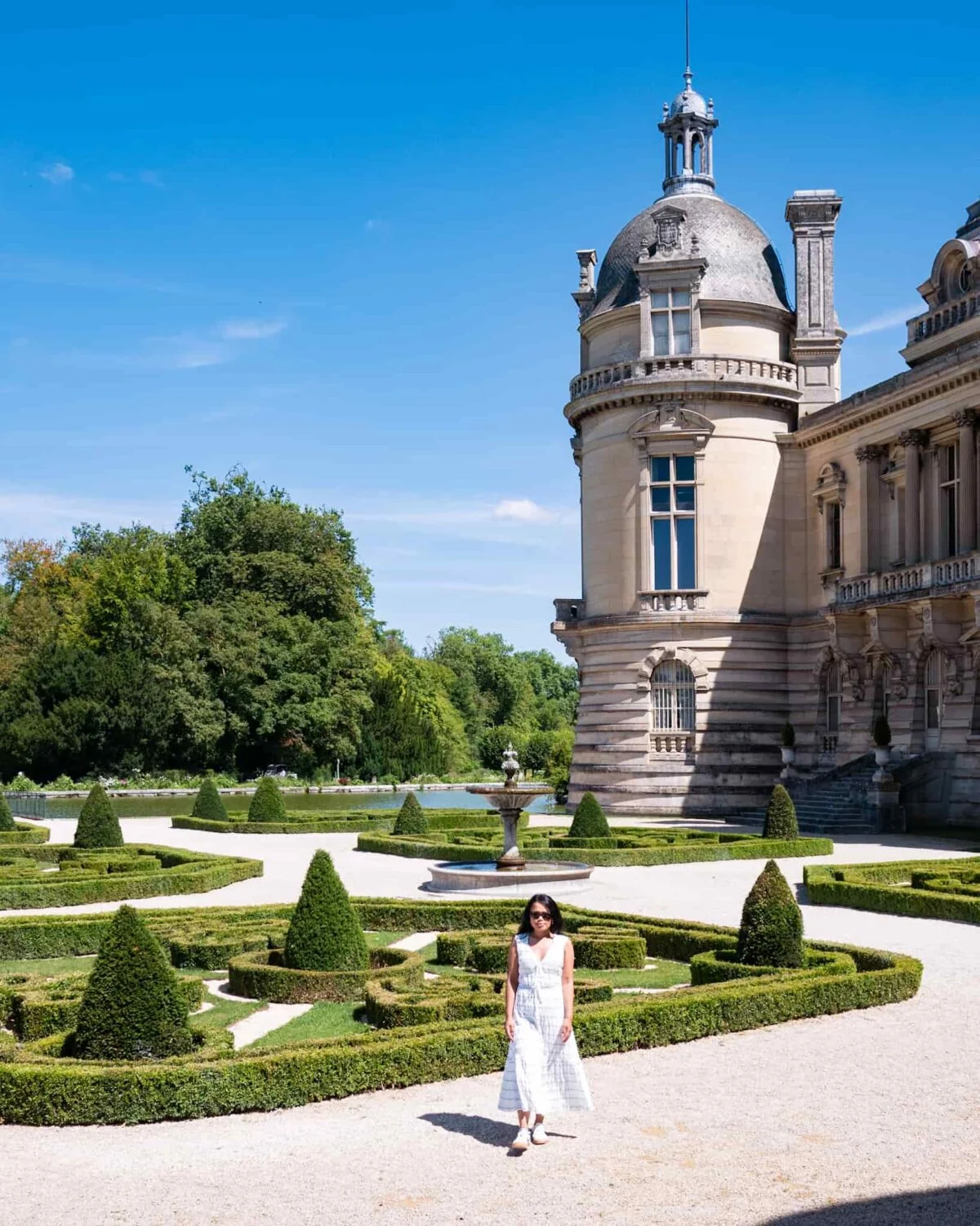 Girl wearing white in the middle of a garden at Chateau de Chantilly grounds