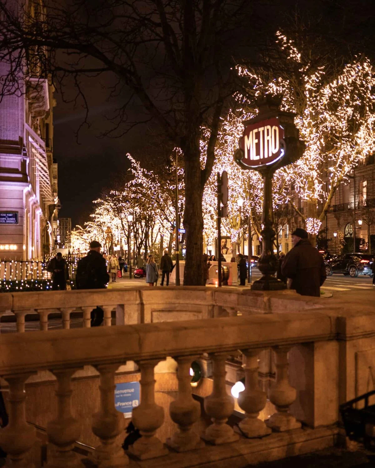 A Paris street lined with trees decorated with lights