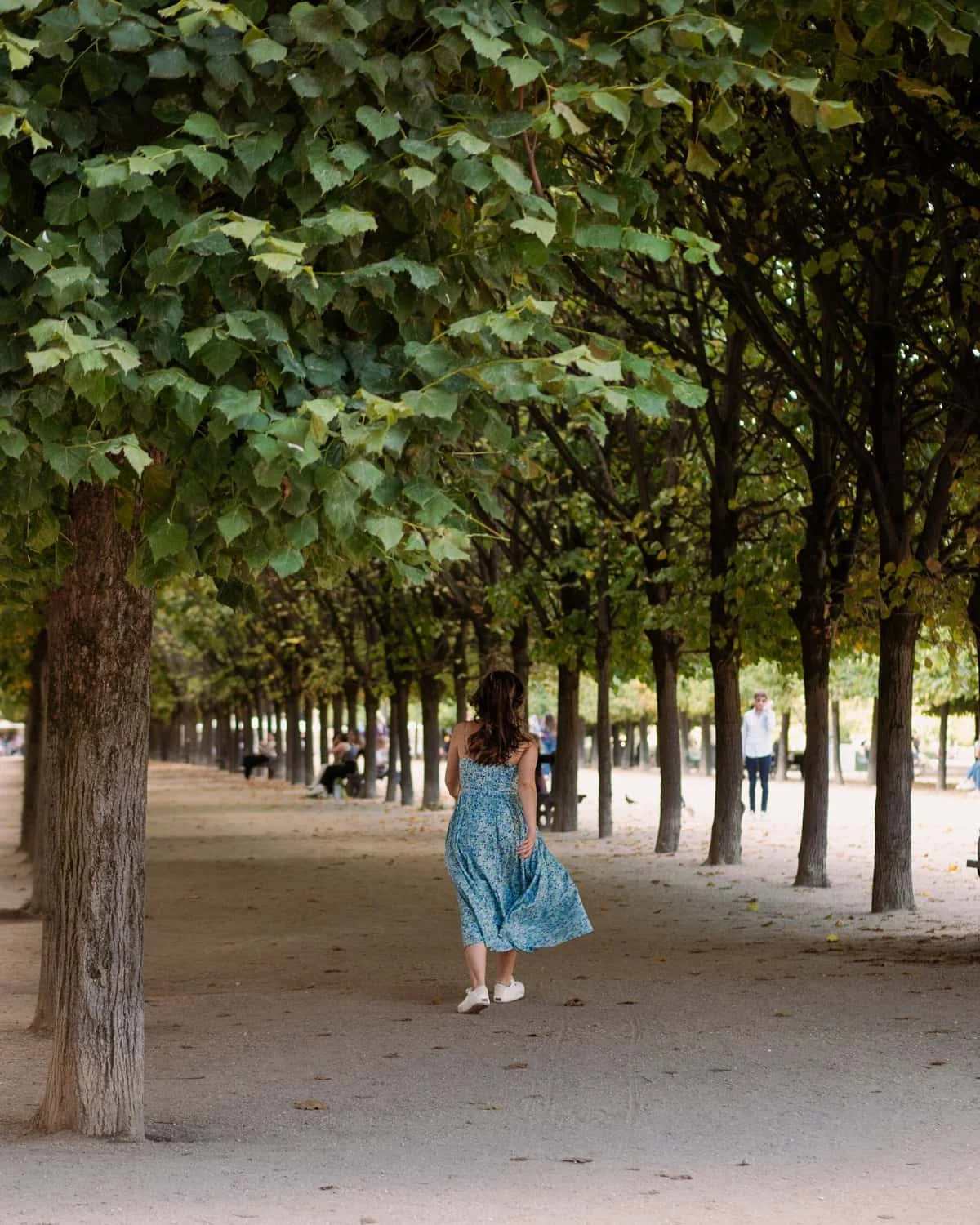 A woman in blue dress walking at Jardin du Palais Royal