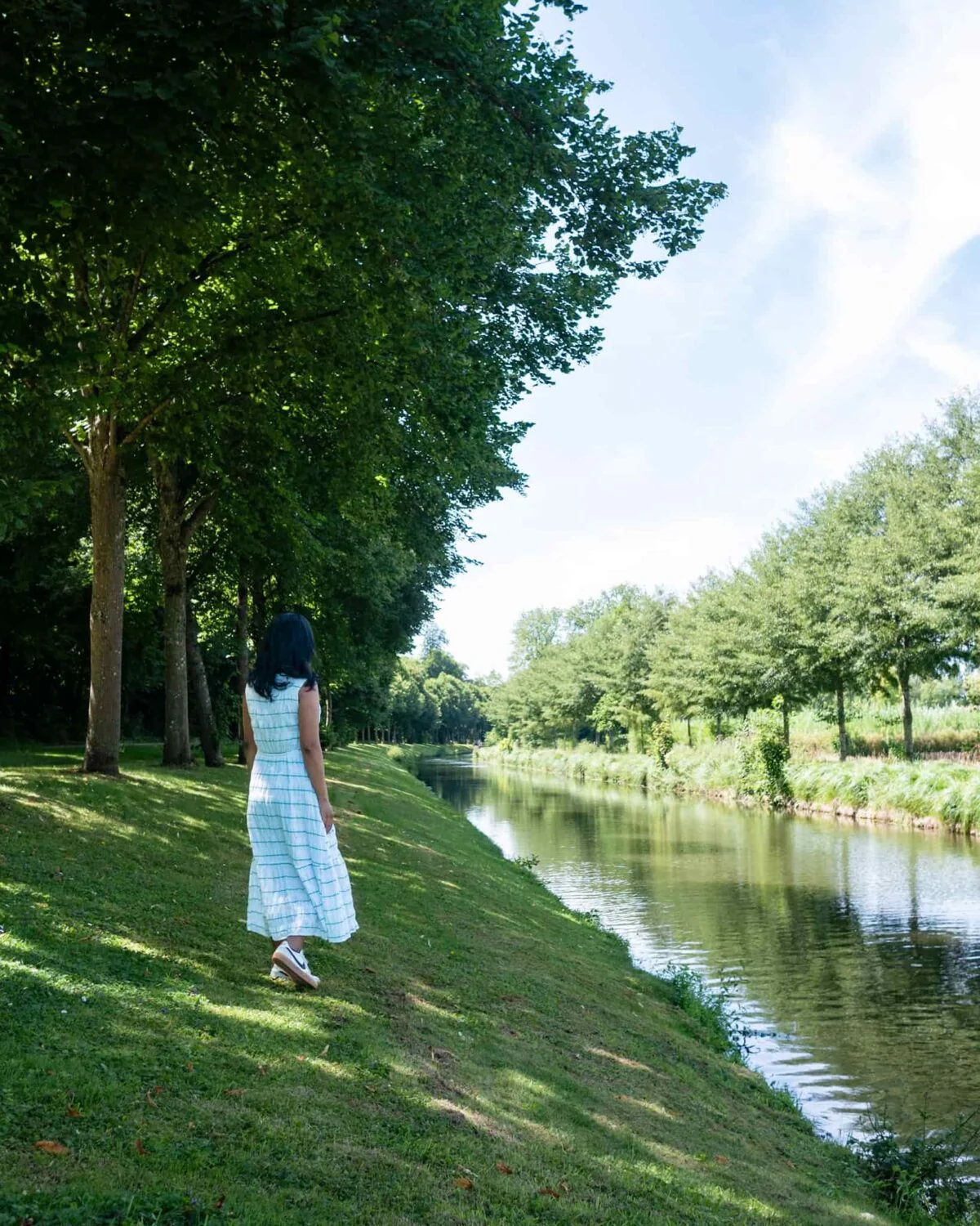 A girl wearing white looking at the canal at Chateau de Chantilly