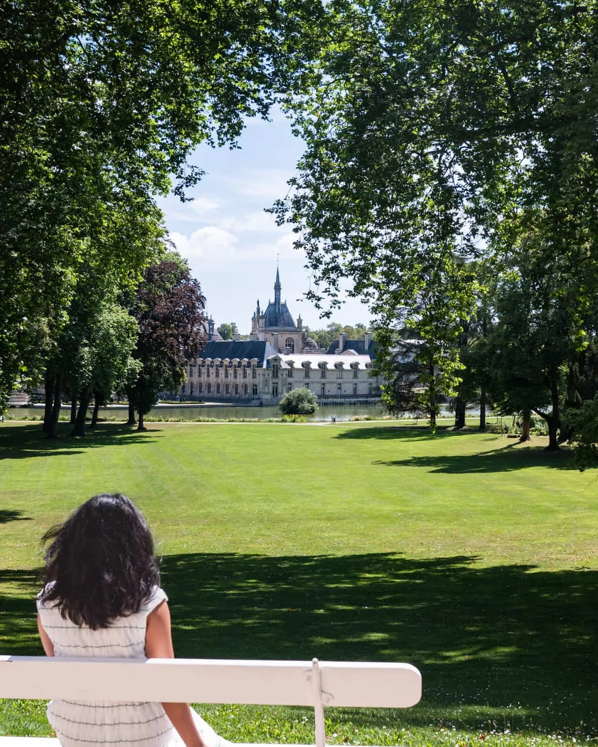 Girl wearing white staring at Chateau de Chantilly grounds
