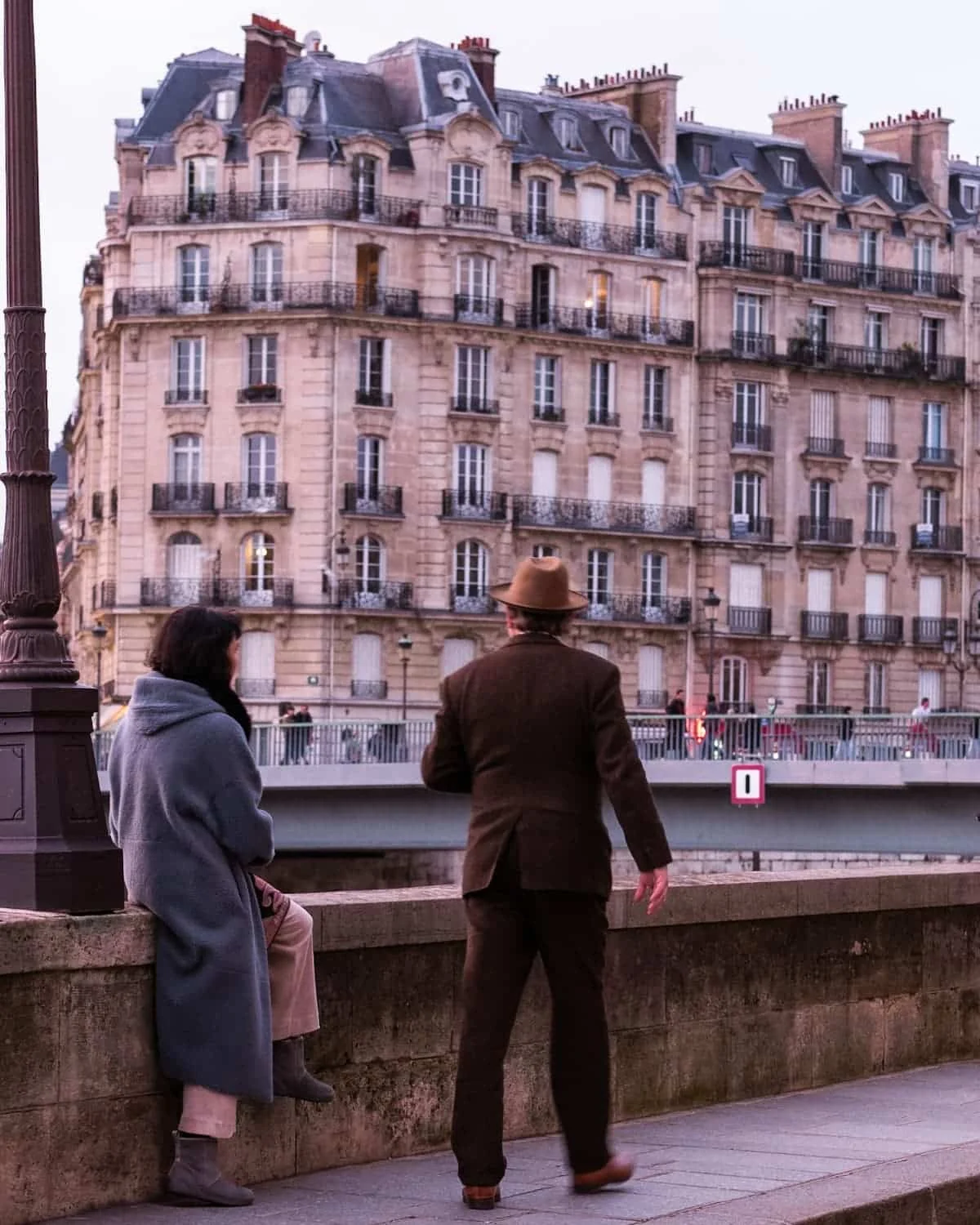 A couple looking at the Seine, with a Parisian façade in the background