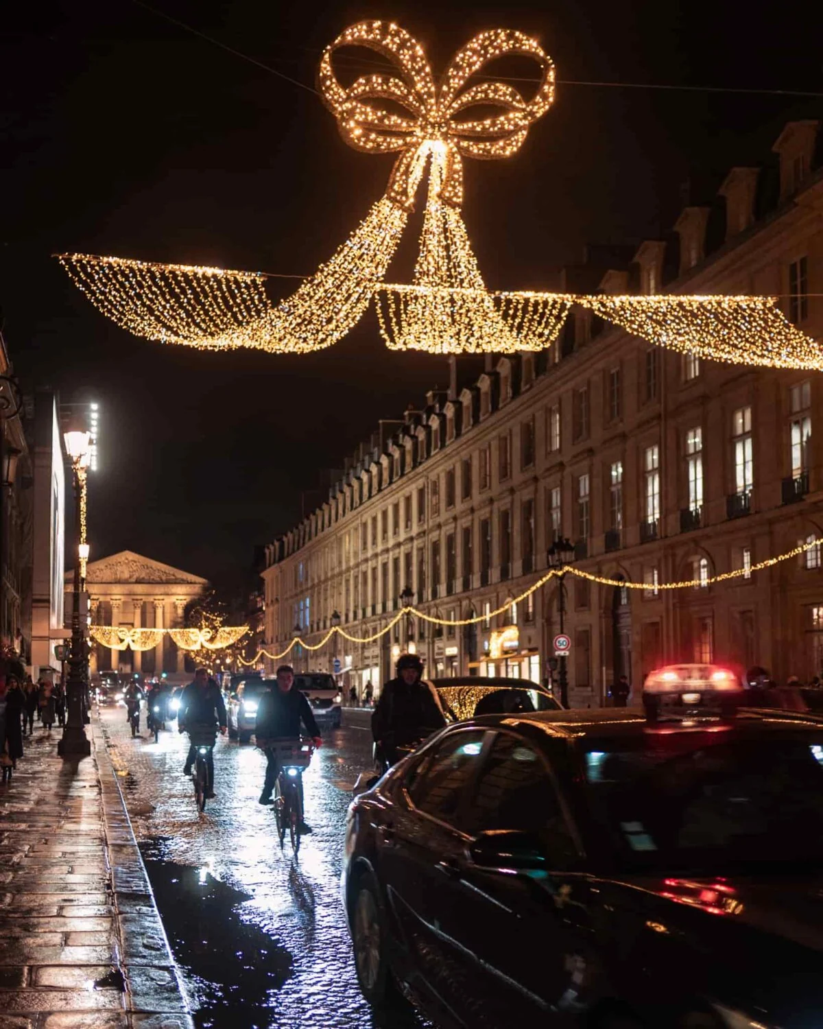 A Paris street with traffic decorated with Christmas lights