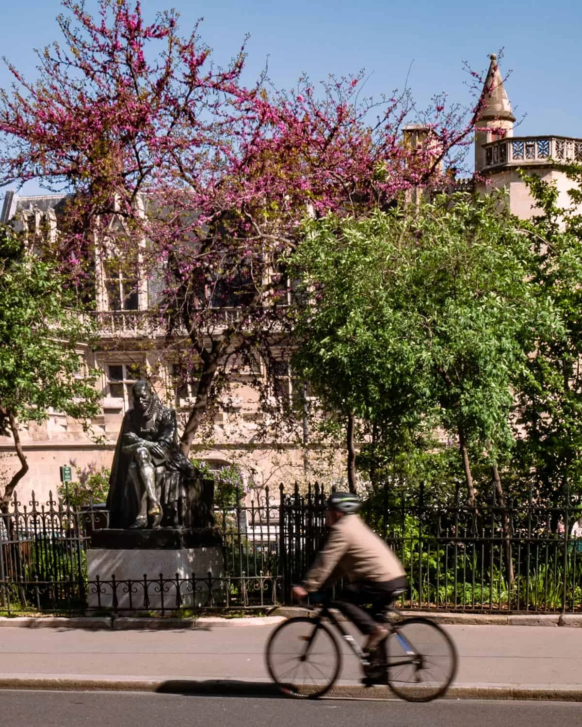 A Parisian cyclist riding past Statue of Michel de Montaigne 