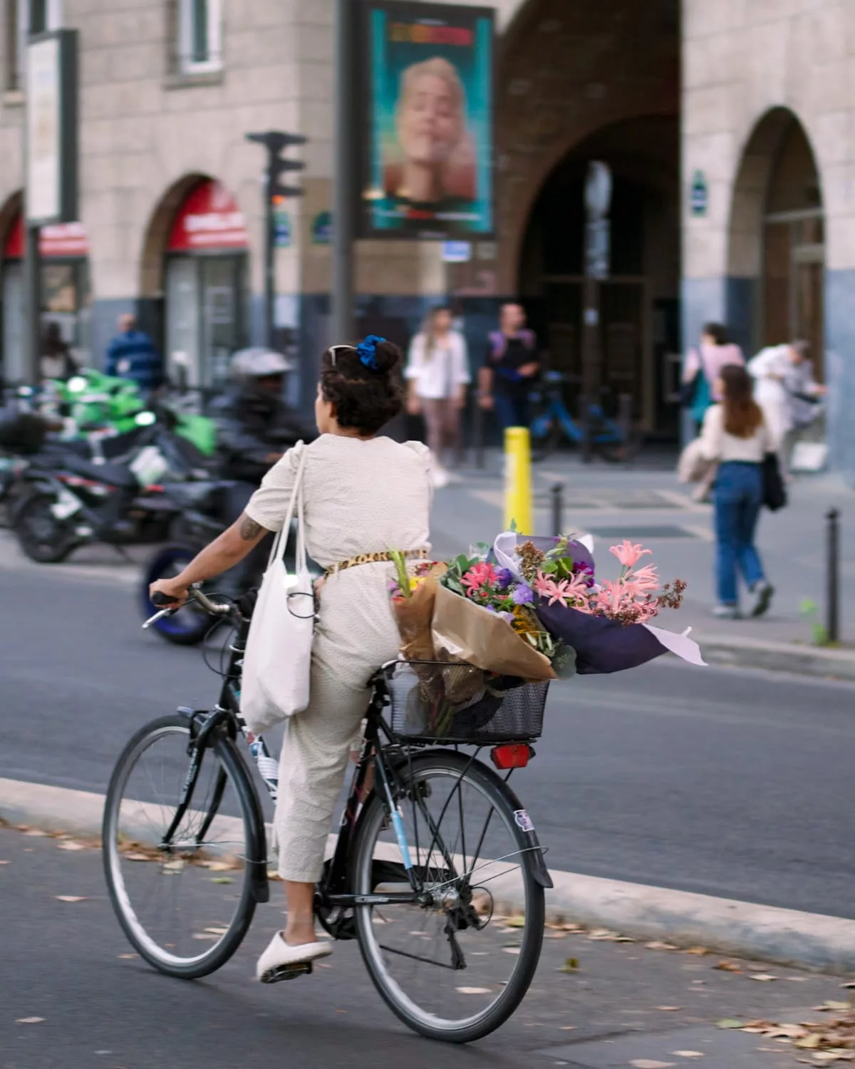 A Parisian woman in a bike with a basked full of flowers